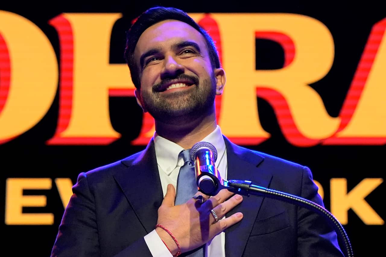 A man wearing a suit placed his hand on his chest while speaking to a microphone