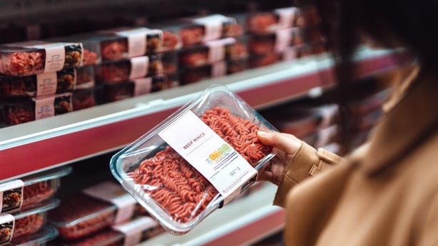 Above the shoulder view of woman holding a pack of beef mince in a supermarke 