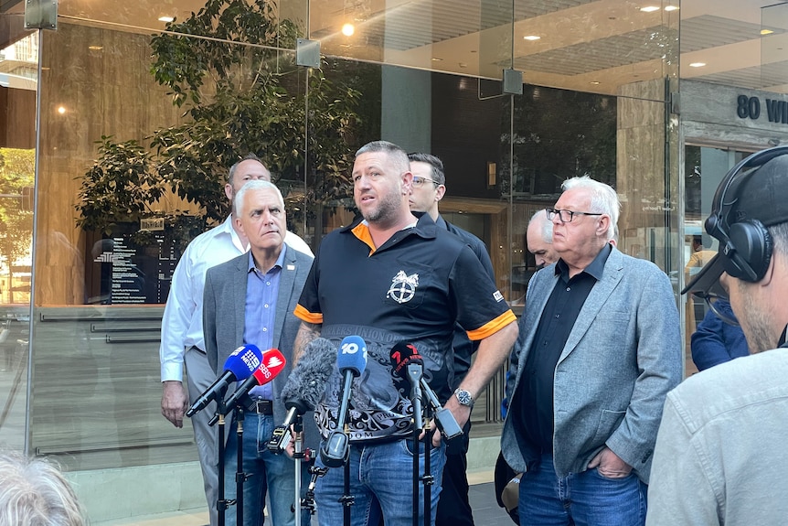 A group of men stand together and give a press conference on the footpath outside an office building in Sydney