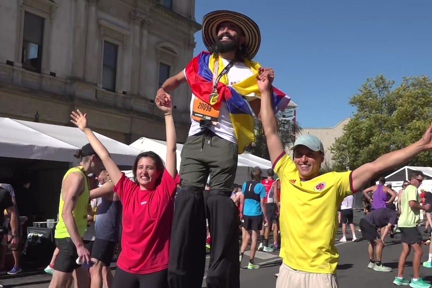 A man holds hands with two people while on stilts
