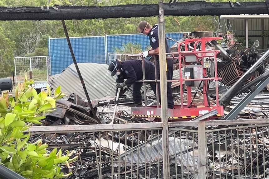 Police investigators among charred remains of a house