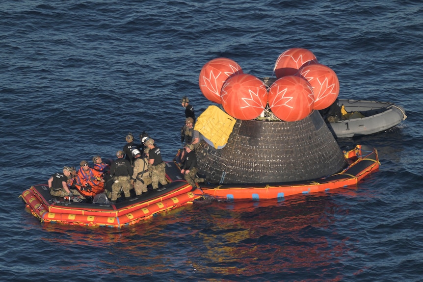 Artemis astronauts are loaded into a raft after successfully splashing down in the Pacific Ocean 