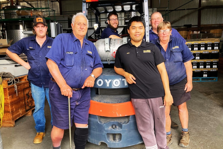 Several men and a woman stand around a forkliftt.