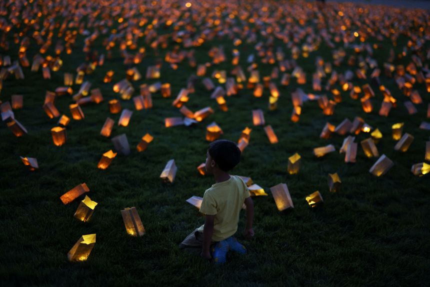 A boy sits on the grass during a vigil in protest against potential cuts to Medicaid in Washington, DC, on July 23, 2025.