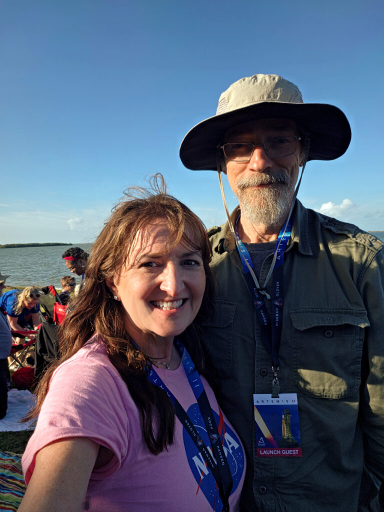 A woman and a man take a selfie outside during a NASA launch.