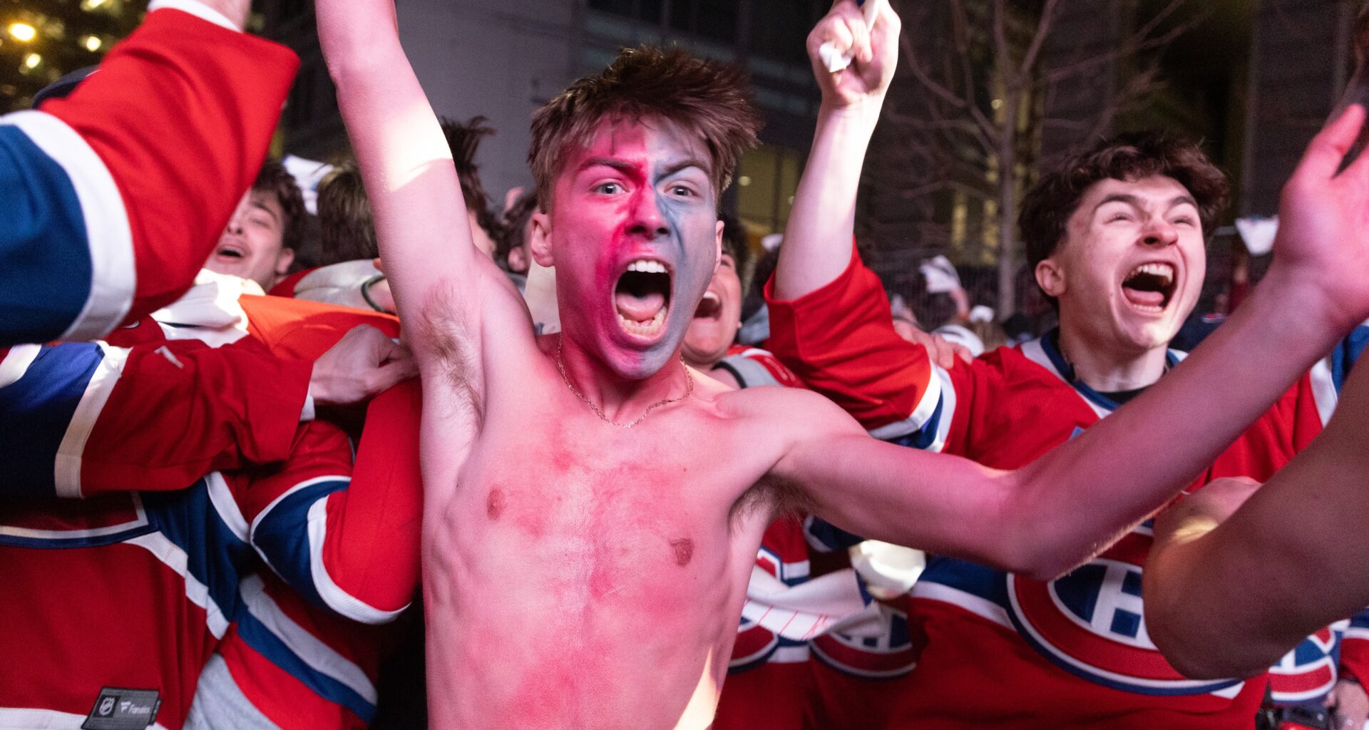 Shirtless Canadiens fan Lyam Péloquin celebrates the team's overtime win with hundreds of other Habs jersey-clad fans surrounding him Friday night outside the Bell Centre.