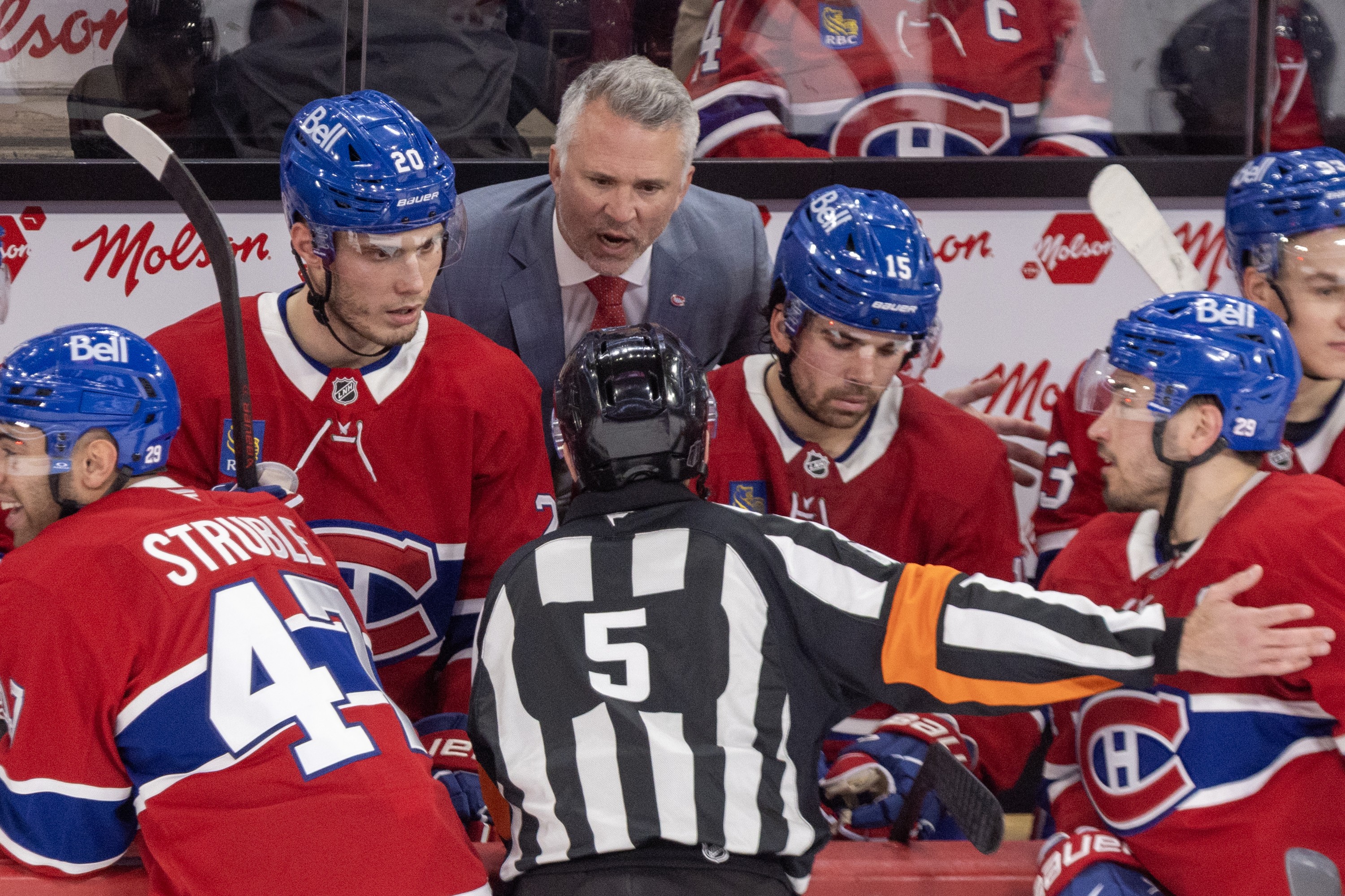 Canadiens head coach Martin St. Louis complains to referee Chris Rooney, seen from behind leaning over the Habs bench.