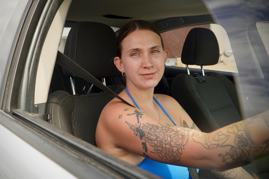 A young woman in the driver's seat of a car.