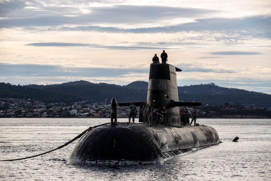 Crew stand on the top of a submarine.