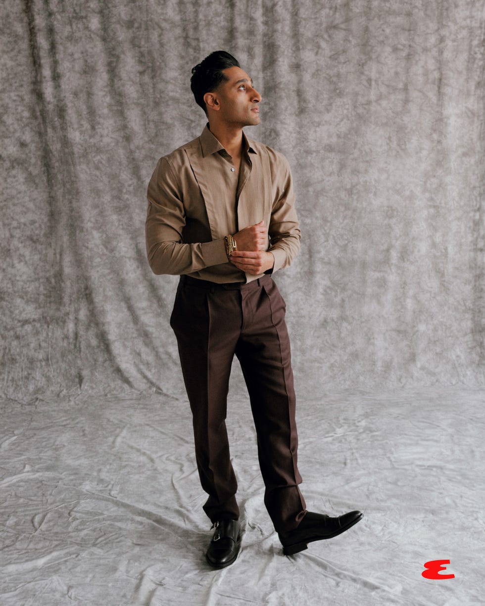 person in formal attire standing against a textured background