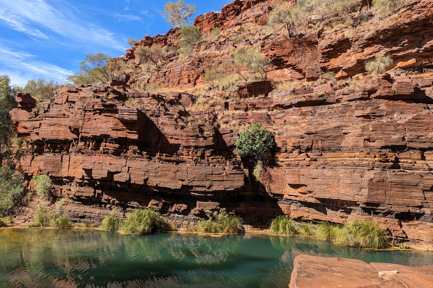 Green water and red rocks beneath a blue sky 