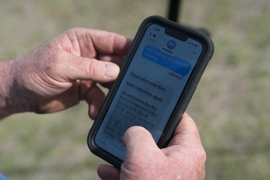 Over the shoulder photo of man's iPhone, showing a text from Ben to VicGrid saying "Still waiting, are you still coming"