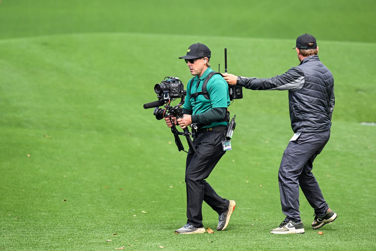 A CBS camera operator films players as they walk off the 18th hole during the continuation of the weather-delayed third round of the 2023 Masters Tournament
