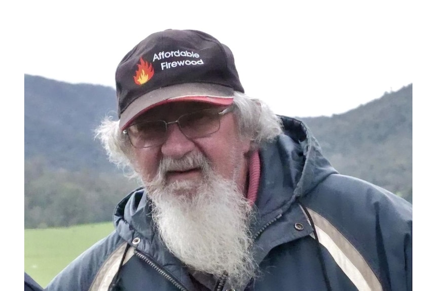 A picture of a man with glasses and a long grey beard and hat looking at the camera