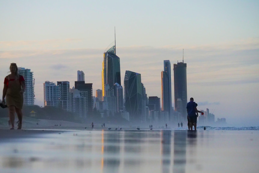 A city skyline with high-rise towers behind a beach.