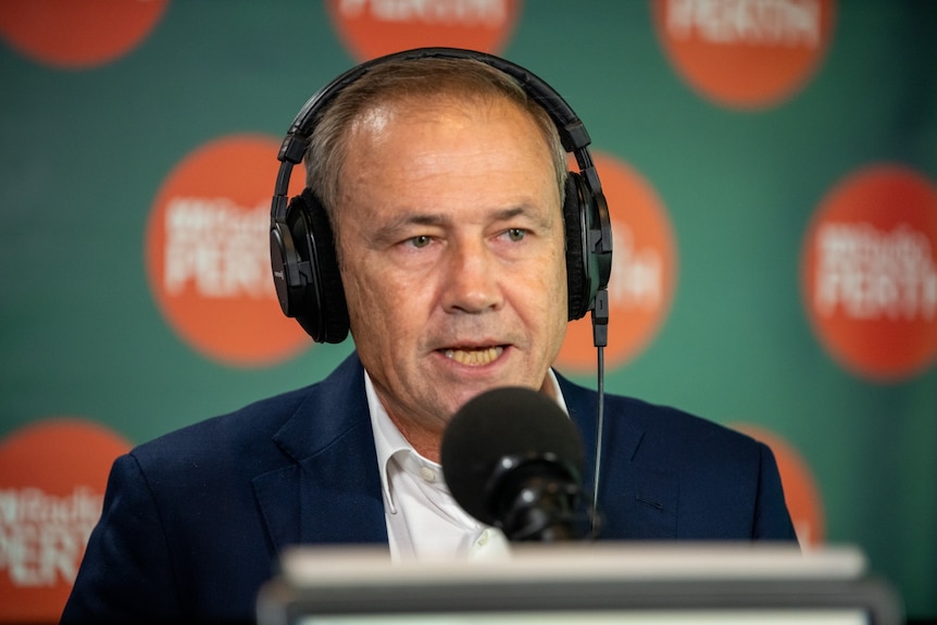 A close-up head and shoulders shot of WA Premier Roger Cook speaking in a radio studio with headphones on during an interview.