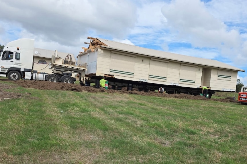 a house on the back of a truck in a field