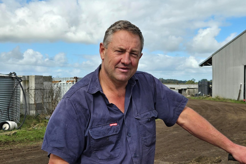 A man kneeling on a motorbike at a farm