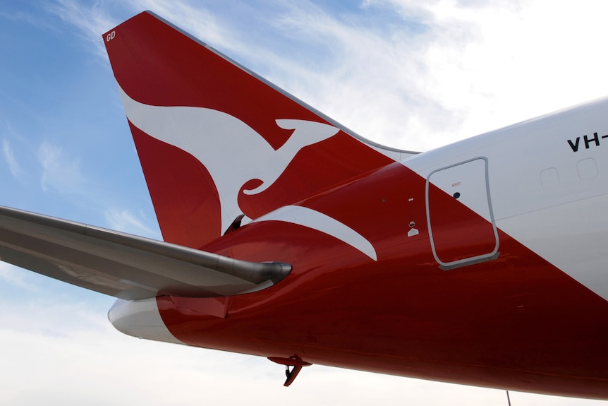 The red Qantas kanmgaroo logo seen on the tail of a white Boeing 767 plane on a background of a blue sky