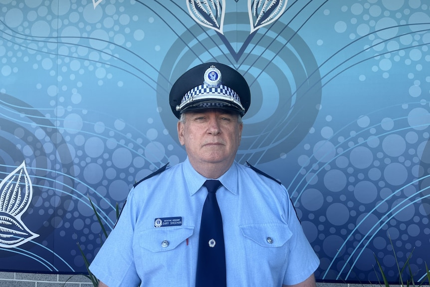 A police man stands in front of a photo