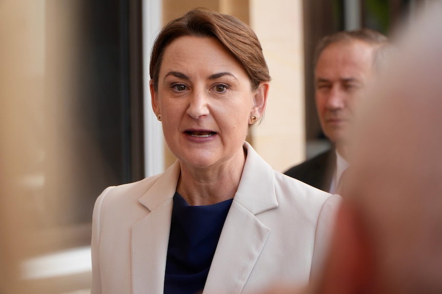 A mid-shot of Amber-Jade Sanderson speaking outside parliament wearing a light-coloured jacket and dark top.