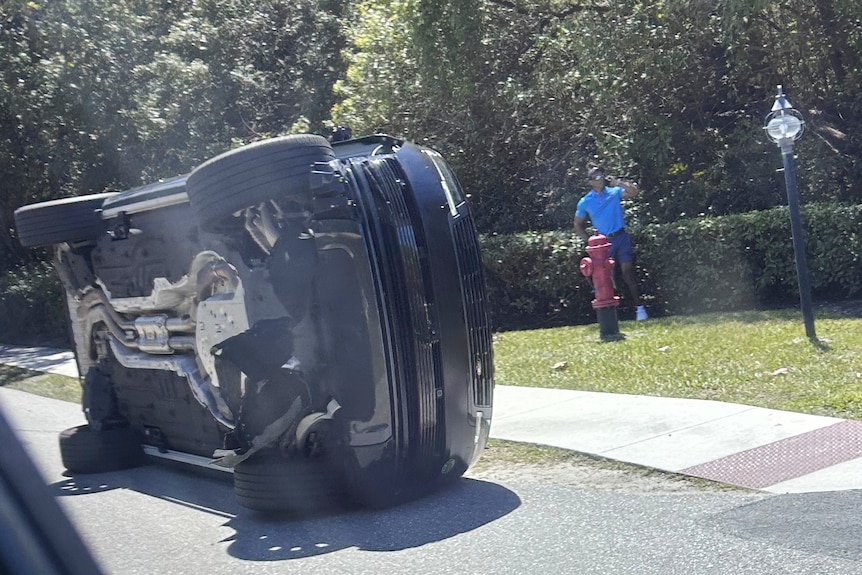 Golfer Tiger Woods stands by his overturned vehicle.