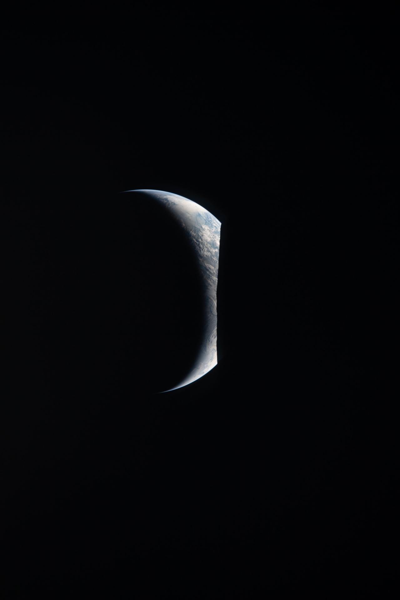 Earth appears as a delicate crescent, with only its upper edge illuminated