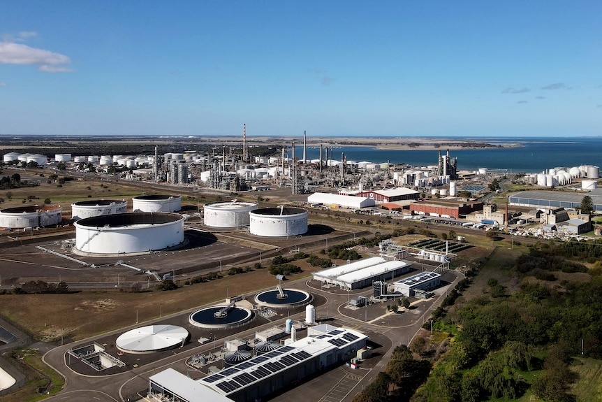 An aerial view of a sprawling oil refinery by the sea.