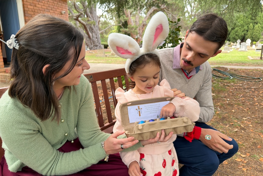 A young couple with their daughter on a bench.