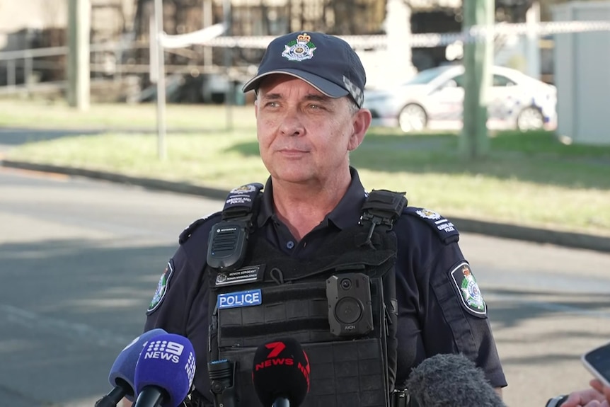A police officer standing in front of microphones 