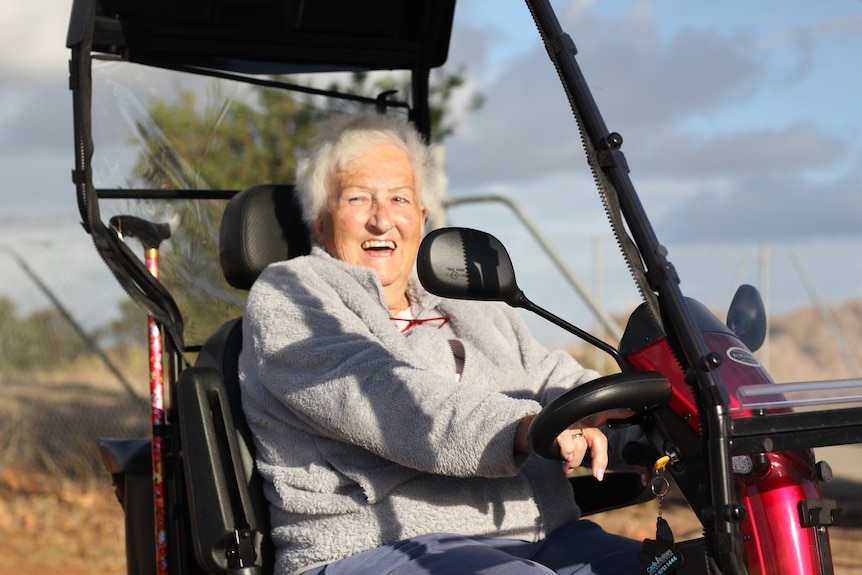 A smiling Jan Whalan rides her mobility scooter.