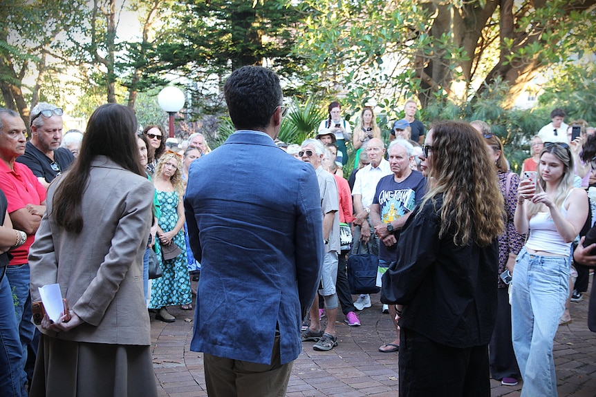 Three councillors standing in front of large crowd.
