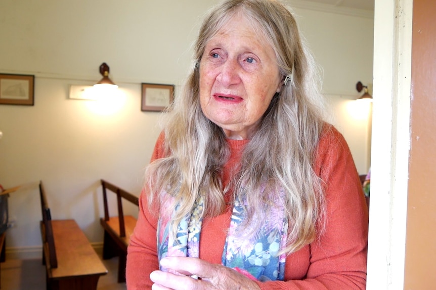 A older woman with long hair, inside a church.