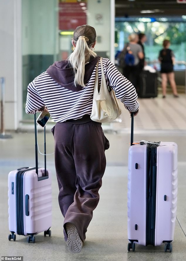 She finished her casual ensemble with a pair of Ugg boots as she wheeled two pink suitcases through the airport