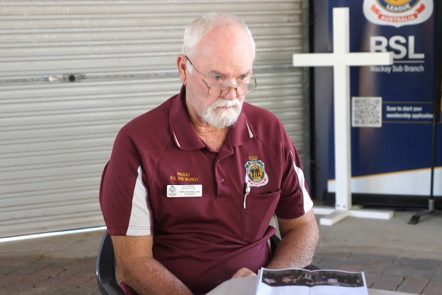 A man sitting inside a shed at a table, with plans in front of him