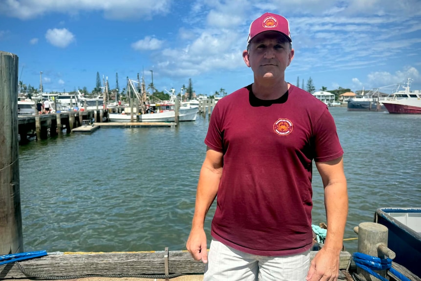 Man standing at dock boats behind him