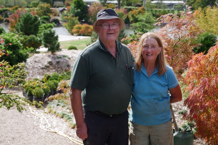 A man and a woman standing in a garden looking at the camera
