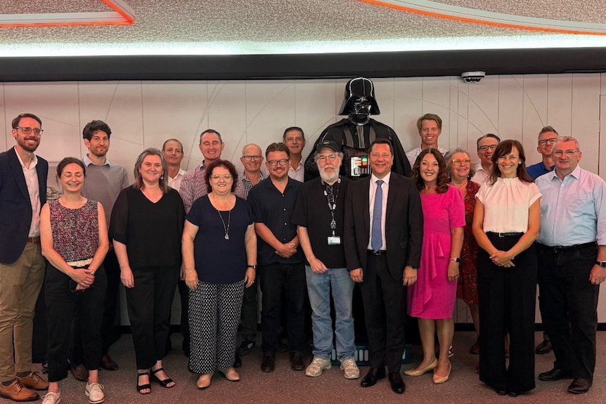 Group of people smiling in front of darthvader