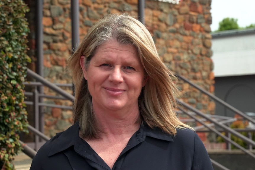 A woman with blonde hair and a black shirt.