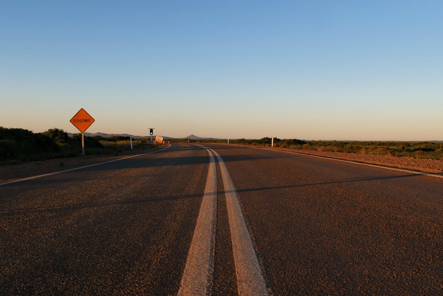 A road in the sunset, the flinders rangers can be seen in the distance