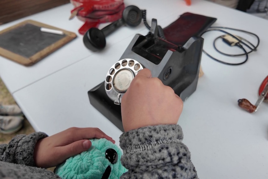 A child dials a rotary phone