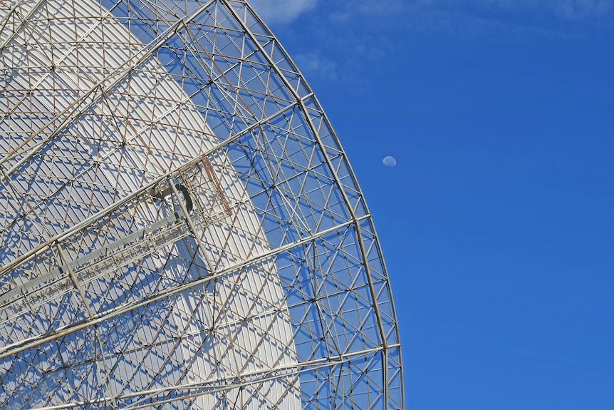 A view of a clear blue daylight sky, with the Parkes Dish and the Moon in the frame.