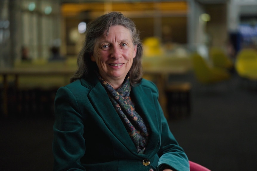 A woman wearing a green jacket smiling