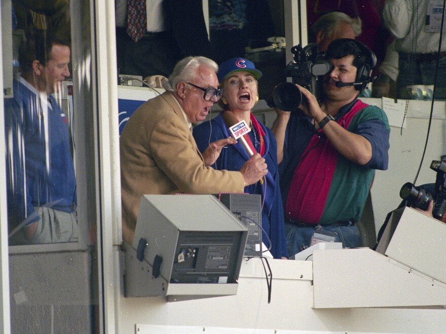 Hillary Clinton, middle, who was First Lady at the time, and Chicago Cubs announcer Harry Caray, left, sing "Take Me Out To The Ball Game" during the seventh inning stretch at Wrigley Field in Chicago in 1994.