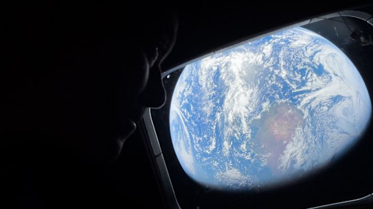 Commander Reid Wiseman looks at the Earth from a window aboard the Orion spacecraft Integrity during the Artemis II mission en route to the moon.