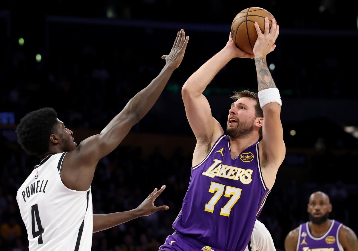 Lakers star Luka Doncic shoots over Brooklyn Nets guard Drake Powell during a Lakers win on March 27.