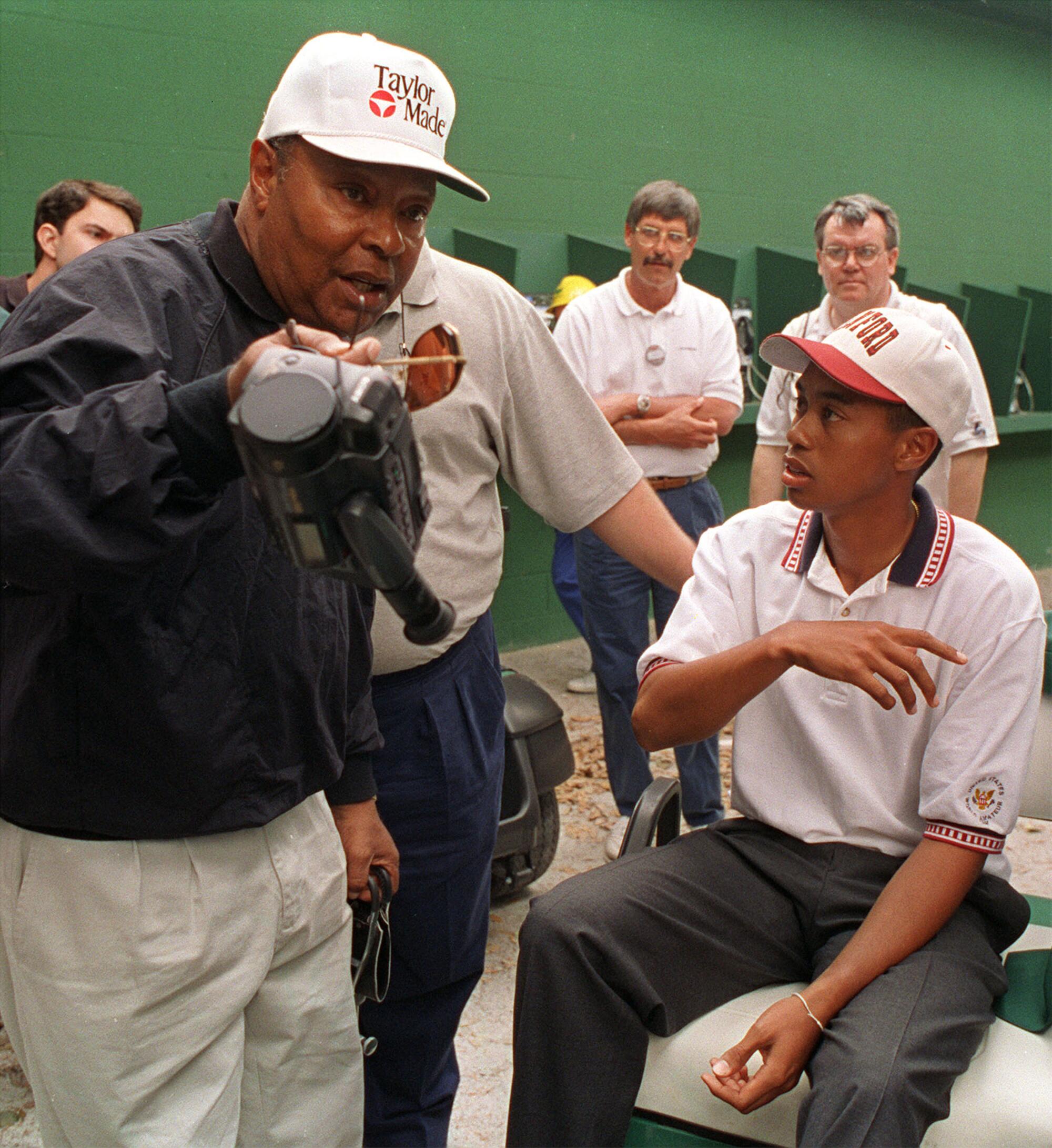 Amateur Tiger Woods, right, talks with his father, Earl Woods, after practice for the Masters golf tournament 