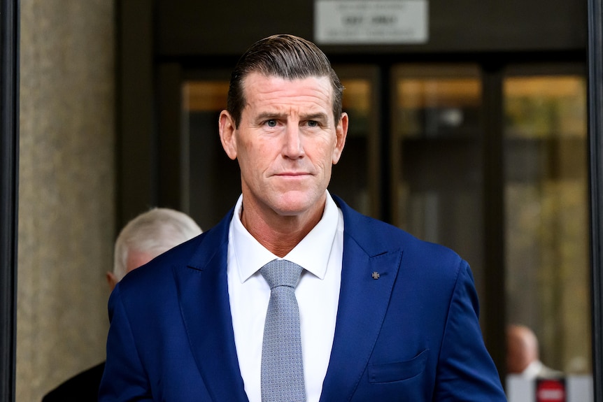 Ben Roberts Smith in a blue suit, white shirt, outside court on a sunny day.