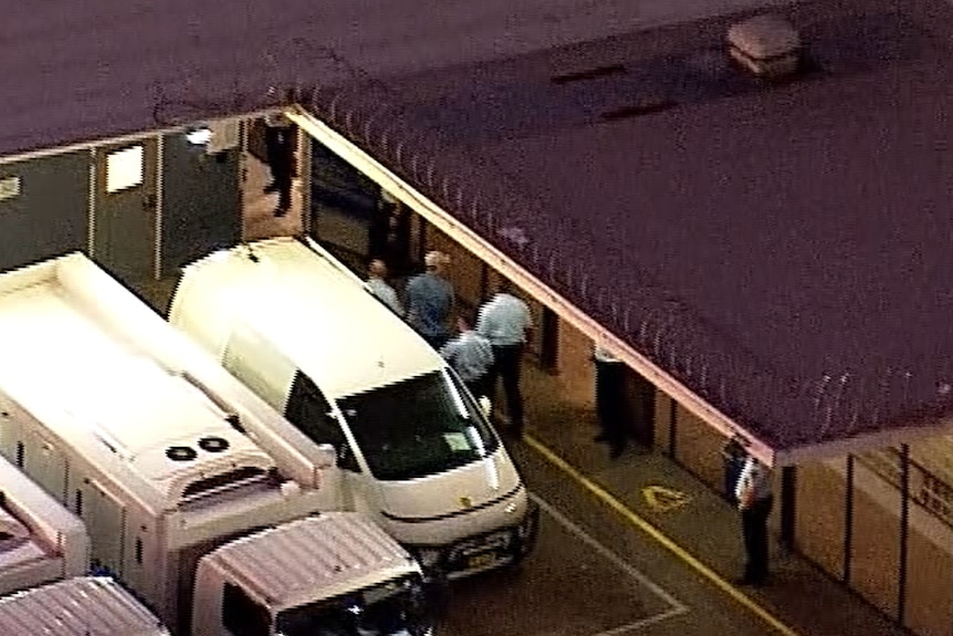 An aerial image of Ben Roberts-Smith being led out of a white van.