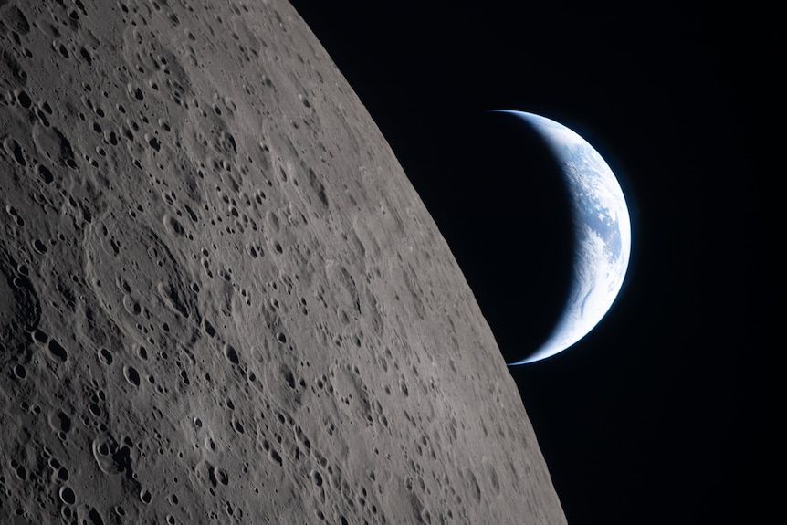 The moons surface with earth in the background